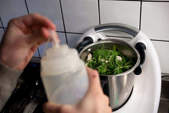 Hands preparing pesto in mixer