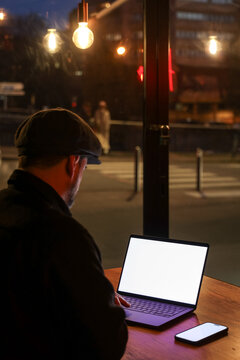 Man Working on Laptop in Cozy Cafe at Night