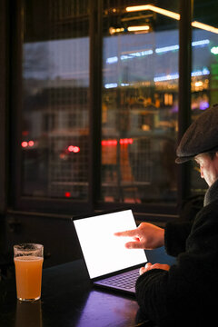 Anonymous Person Using Laptop in a Bar at Night