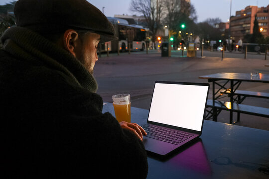 Man working on laptop with blank screen at dusk