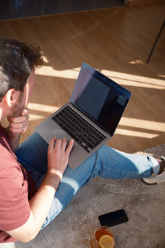 Crop of anonymous man using laptop indoors