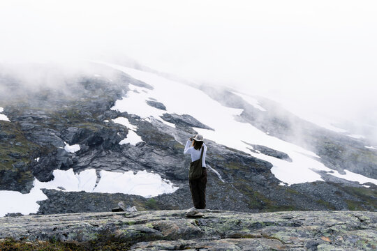 A woman takes pictures on a mobile phone in the mountains