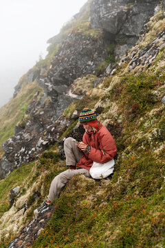A woman uses a mobile phone sitting on a rock