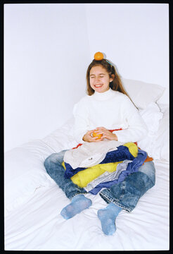Girl sitting on bed wearing colorful clothes with an orange