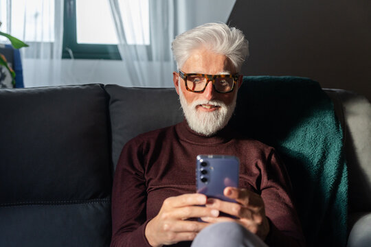 Senior Man Smiling While Using Smartphone