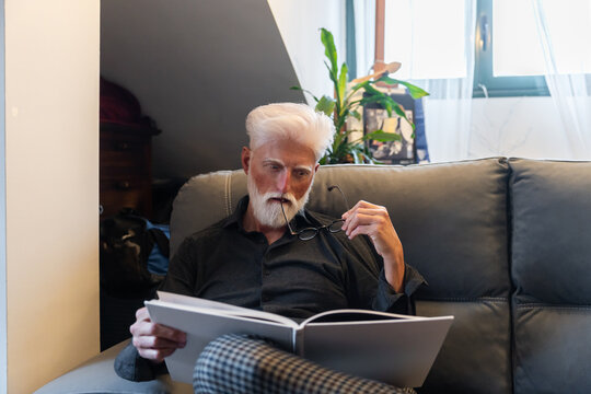Thoughtful Senior Man Reading At Home