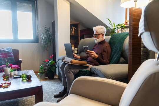 Senior Man Working on Laptop and Phone at Home
