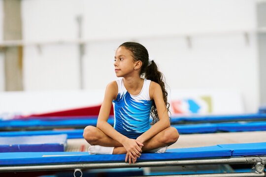 Thoughtful Gymnast Seated on Trampoline