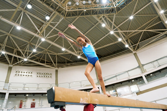 Gymnast Practicing on Beam Under High Ceiling