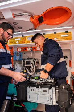 Paramedics preparing medical equipment inside ambulance