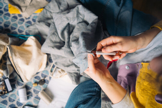 Hands with fabric using seam ripper