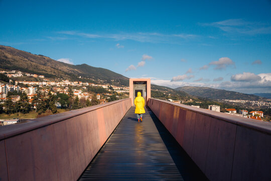Person in yellow raincoat walking on a bridge