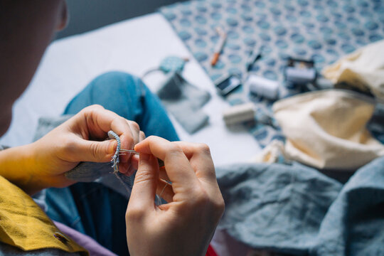 Hands sewing fabric with needle and thread