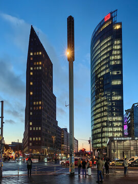 Berlin, Germany-January 14th 2026: Modern evening view of Potsdamer Platz in Berlin with illuminated BahnTower, Kollhoff Tower, traffic and people under a blue dusk sky.