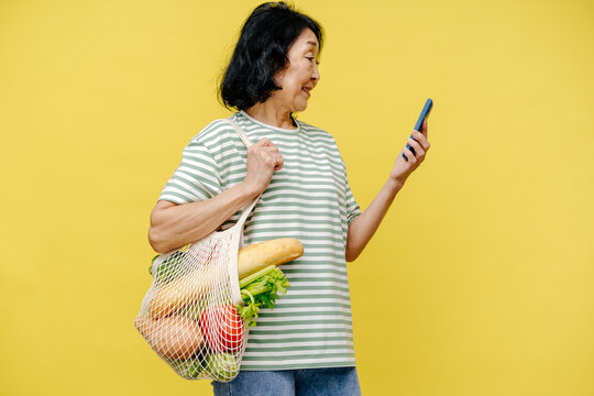 Senior Woman Checking Phone While Carrying Groceries