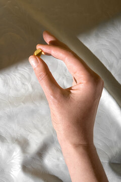 Hand holding omega 3 capsule in sunlight. Studio shot with copy space