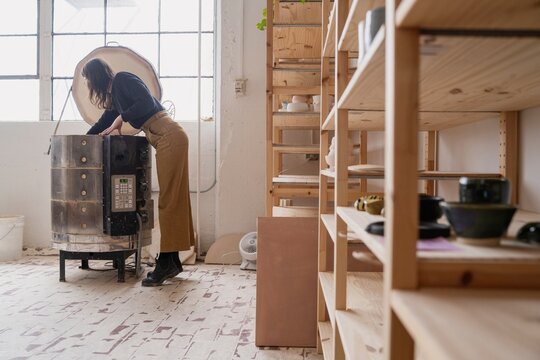 Potter Inspecting Kiln in Ceramics Studio  
