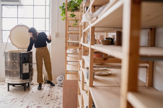 Potter Checking Kiln in Ceramics Studio  
