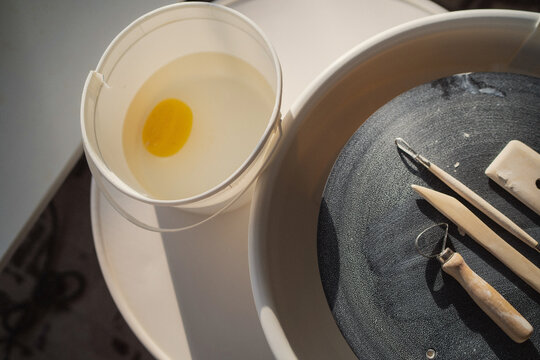 Pottery wheel with sculpting tools and water  
