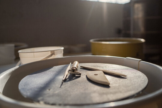 Pottery wheel with sculpting tools in soft sunlight  
