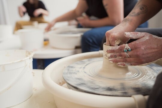 Hands shaping clay on a pottery wheel  
