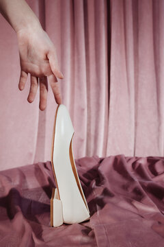 Fashion detail with trendy shoe and hand on pink background