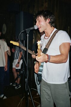 A Young Man Sings And Plays Guitar in a Band at a Concert