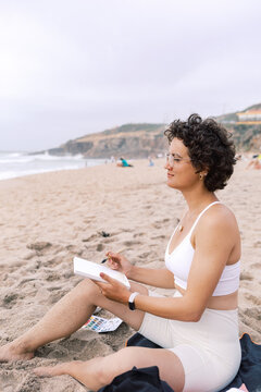 Artist Writing on a Watercolor Postcard While Sitting on the Beach
