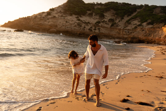 A father and son playing together on the beach at golden time.