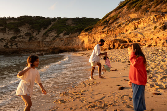 A family playing together at the beach, at golden time.
