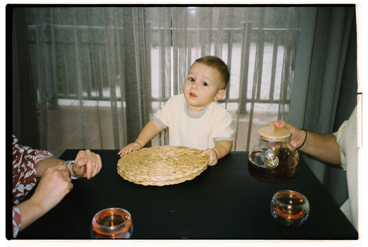 Child at a table with woven plate and tea, enjoying family time