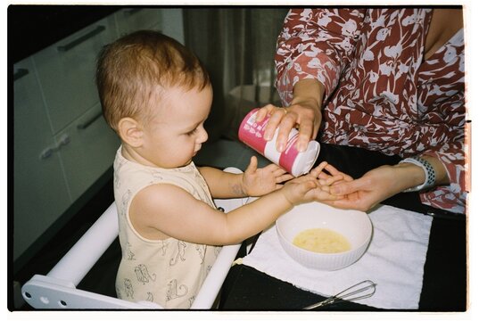 Toddler enjoying a playful moment while adding seasoning to food