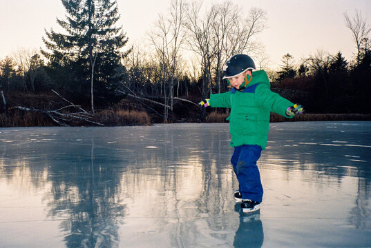 Film photo of a child learning to skate on wild pond ice