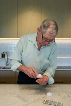 Older man managing medication at modern kitchen counter