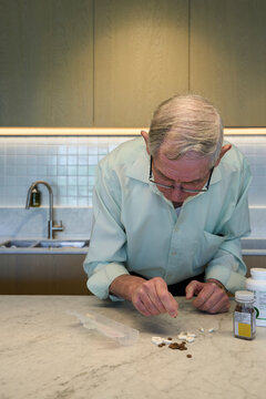 An older man sorts pills into a weekly organizer