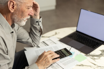 Man analyzing bills and financial documents at home office desk in the morning