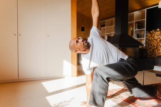 Man Practicing Revolved High Lunge Yoga Pose in Log Cabin Home