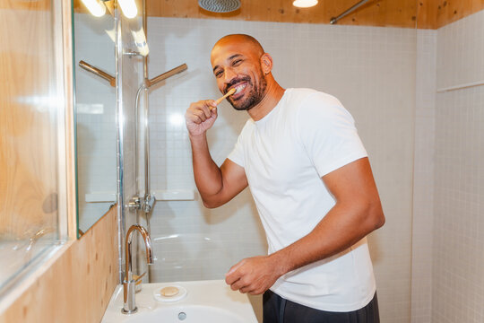 Bald Man Brushing Teeth in Bathroom, Starting His Morning Routine