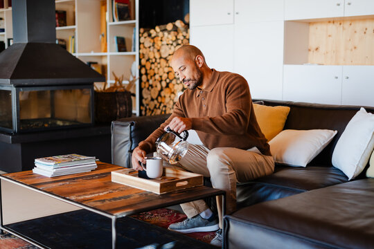 Bald Man Enjoying Tea Preparation in Cozy Log Cabin