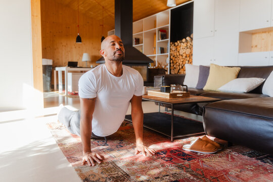 Active Man Practicing Cobra Pose Indoors on a Bright Sunlit Morning