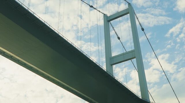 Low Angle View of a Modern Suspension Bridge Tower and Cables Against a Blue Sky