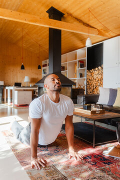 Active Man Practicing Cobra Pose Indoors on a Bright Sunlit Morning