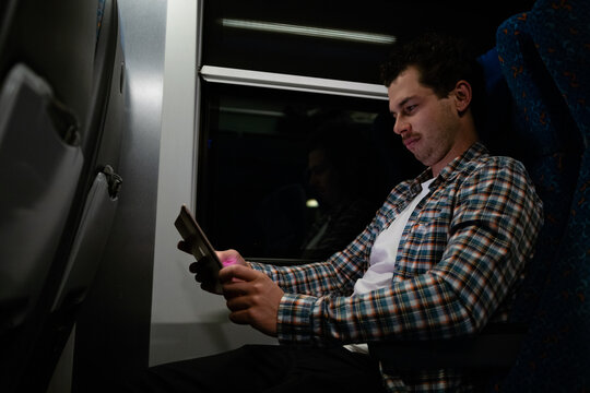 Man sits in train with tablet.