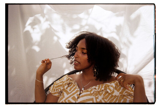 Wide angle portrait of young woman playing with her curly hair