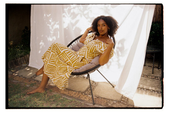 Wide angle portrait of young woman laying back in a round chair
