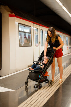 A woman with her son in a stroller are waiting for the train