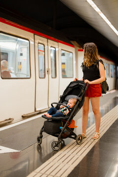 A woman with her son in a stroller are waiting for the train