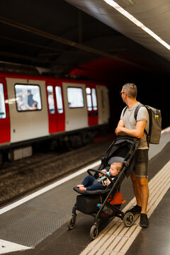 A man with his son in a stroller are waiting for the train