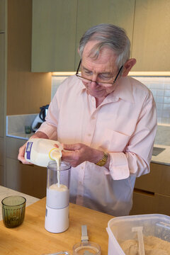 Elderly man preparing a smoothie in a modern kitchen