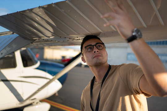 Young Pilot Conducts Close Visual Inspection Under Wing Before Flight